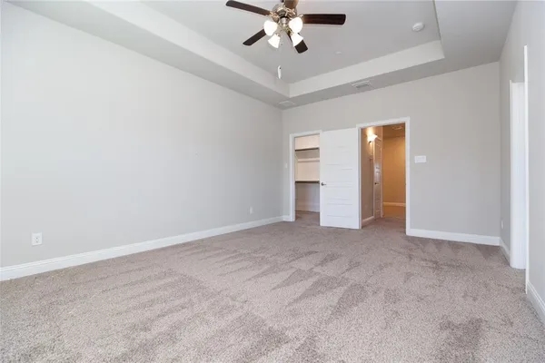 an empty room with closet and a ceiling fan