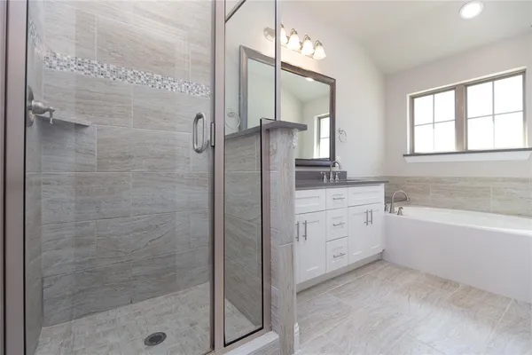 a bathroom with a granite countertop sink a mirror a bathtub and next to a window