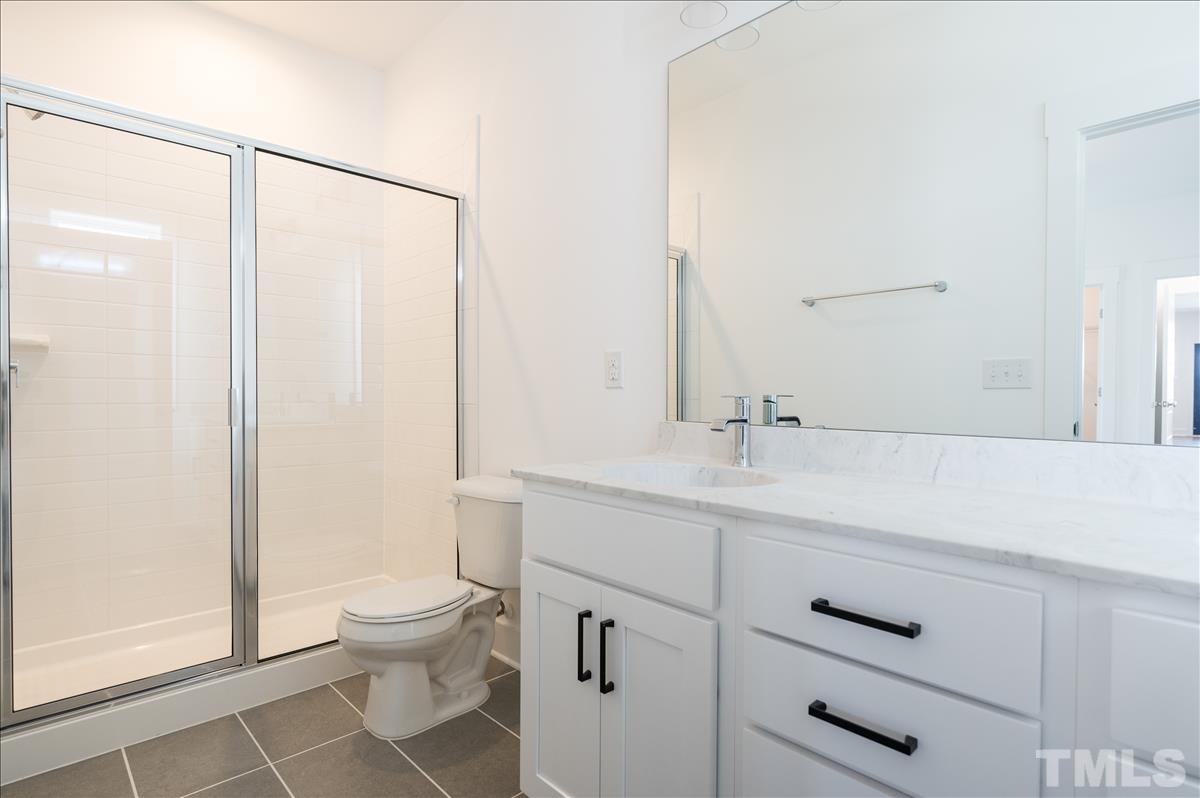 205 Daniel Ridge Road, Unit 1232 Wendell, NC 27591 - Photo 16 of 26 a bathroom with a sink a toilet a mirror and shower