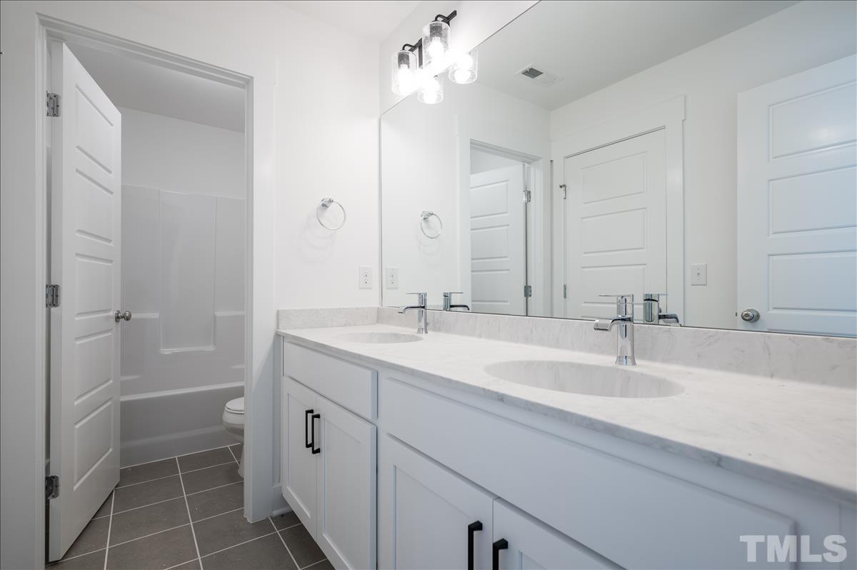 205 Daniel Ridge Road, Unit 1232 Wendell, NC 27591 - Photo 22 of 26 a bathroom with a double vanity sink mirror and a shower