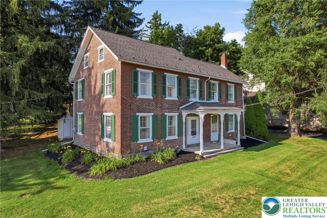 4682 Steuben Road Bethlehem, PA 18020 - Photo 2 of 79 A stately brick residence with green shutters and a welcoming porch, nestled amidst lush trees.