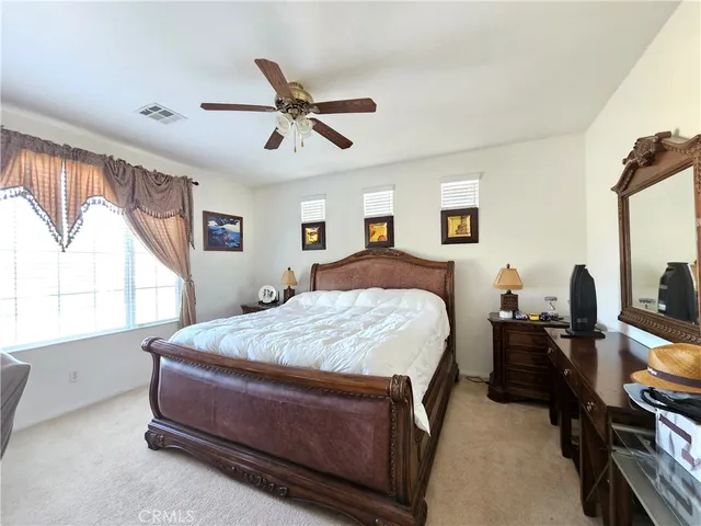 a spacious bedroom with a bed a window and dresser