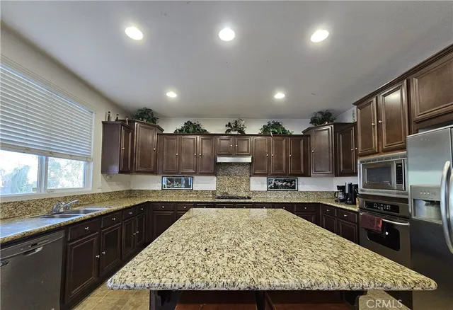 a kitchen with kitchen island granite countertop a sink stove and refrigerator