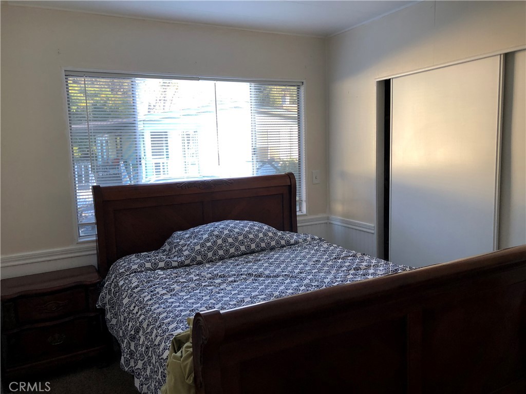 4901 Green River Road, Unit 113 Corona, CA 92878 - Photo 13 of 22 a bedroom with a bed wooden floor and a large window