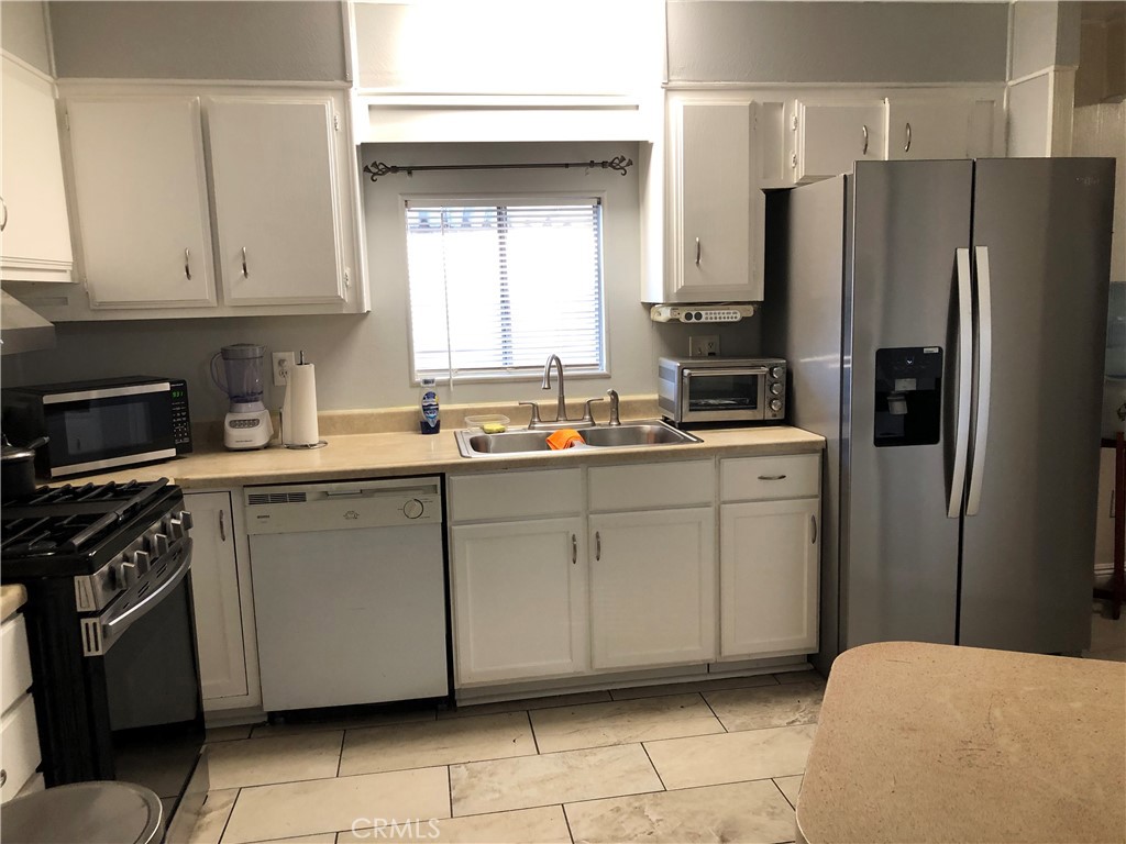 4901 Green River Road, Unit 113 Corona, CA 92878 - Photo 6 of 22 a kitchen with white cabinets a refrigerator and a sink