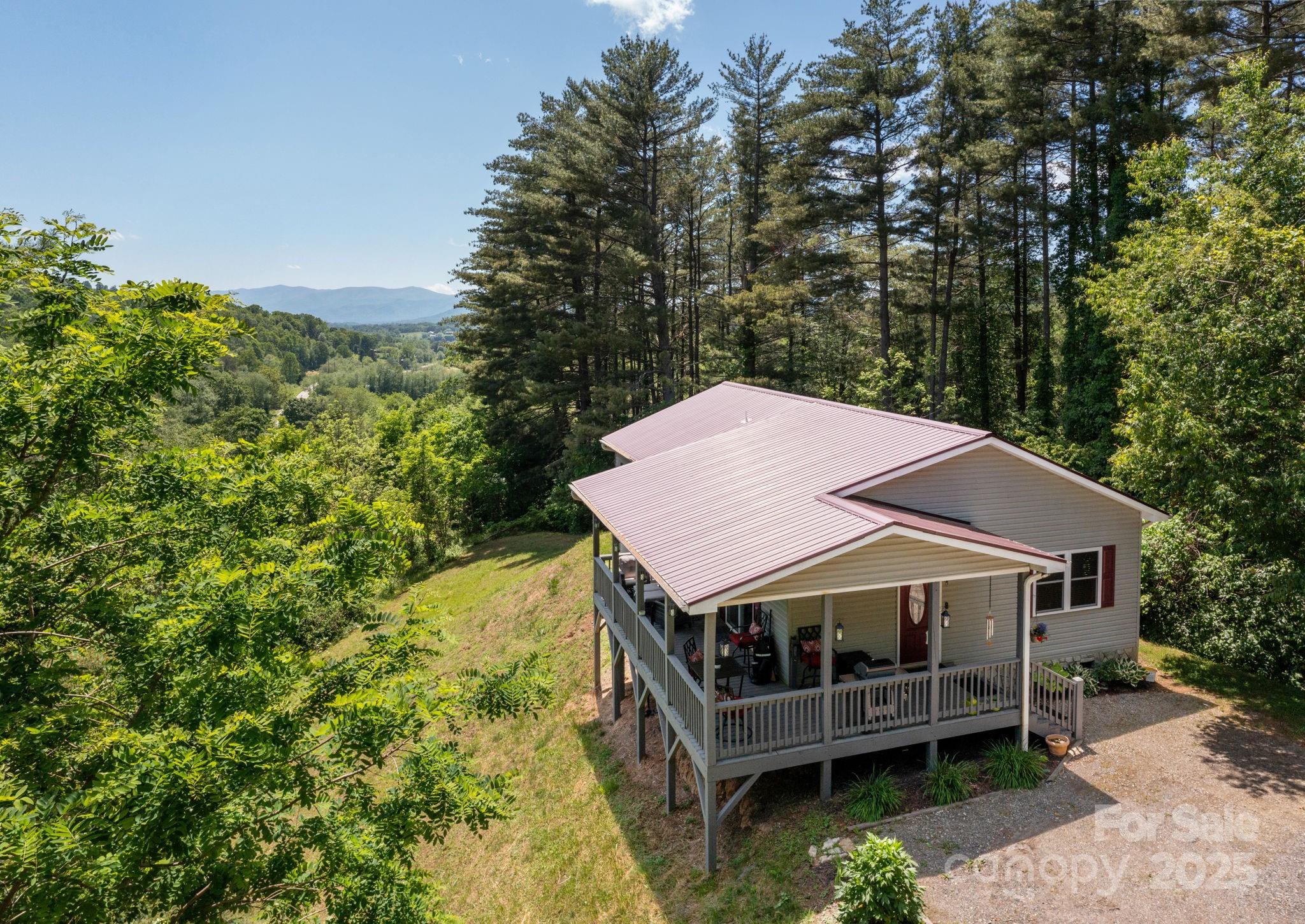 a view of a white house with a big yard plants and large trees