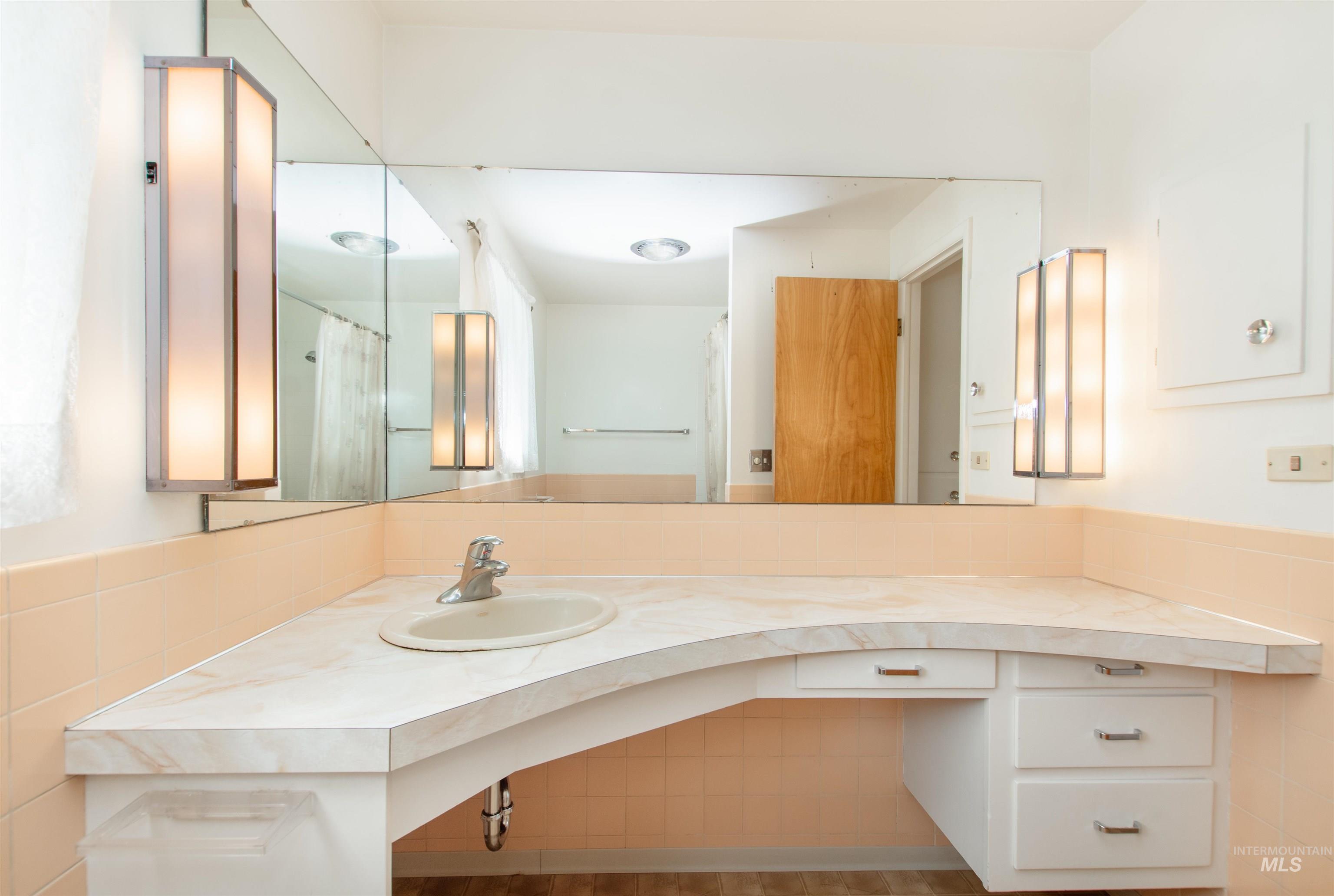 2716 North Redway Road Boise, ID 83704 - Photo 18 of 36 Extended vanity with integrated sink, full-width mirror, built-in cabinetry, and wall-mounted light fixtures