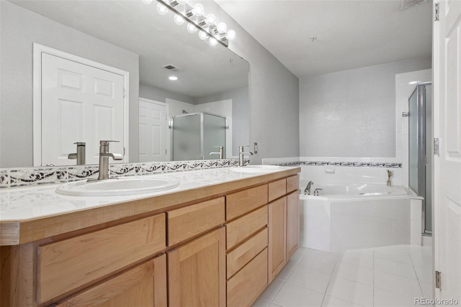 1747 Pearl Street, Unit 106 Denver, CO 80203 - Photo 16 of 26 a bathroom with a double vanity sink a mirror and a bathtub