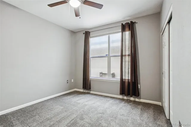 an empty room with windows and ceiling fan