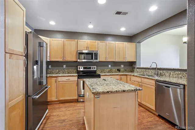 a kitchen with stainless steel appliances granite countertop a refrigerator a stove top oven a sink and dishwasher