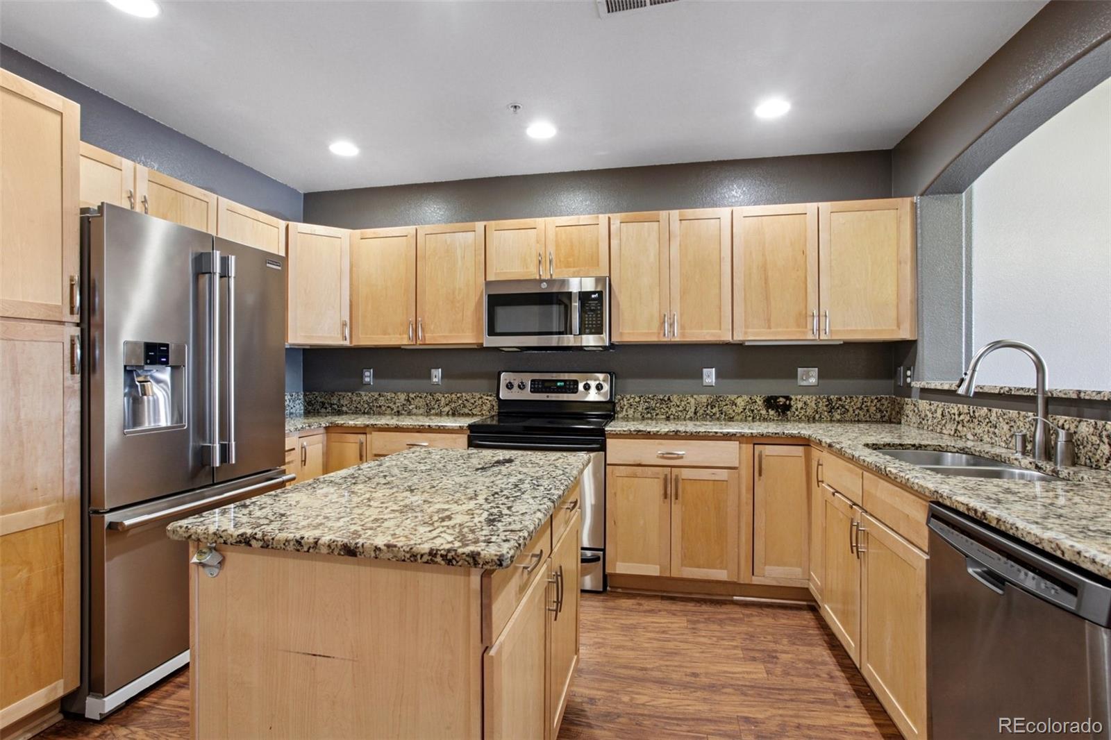 1747 Pearl Street, Unit 106 Denver, CO 80203 - Photo 6 of 26 a kitchen with stainless steel appliances granite countertop a refrigerator stove microwave and sink