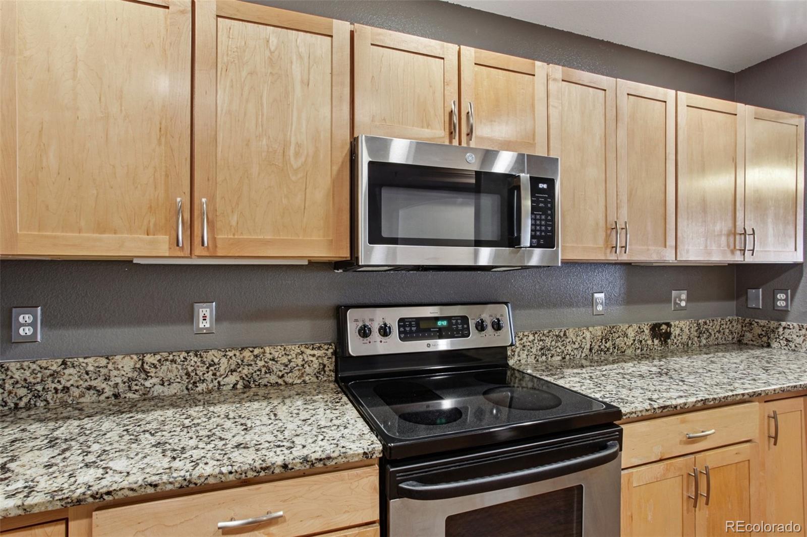 1747 Pearl Street, Unit 106 Denver, CO 80203 - Photo 7 of 26 a kitchen with granite countertop cabinets stainless steel appliances and a counter space