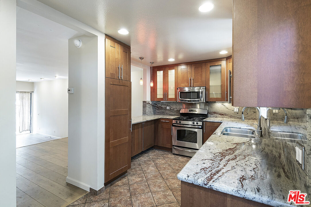 2216 South Bentley Avenue, Unit 10 Los Angeles, CA 90064 - Photo 11 of 40 a kitchen with granite countertop stainless steel appliances and wooden cabinets