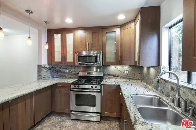 a kitchen with kitchen island granite countertop a sink stainless steel appliances white cabinets and window