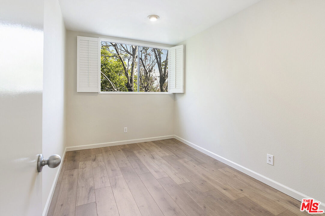 2216 South Bentley Avenue, Unit 10 Los Angeles, CA 90064 - Photo 30 of 40 an empty room with wooden floor and windows