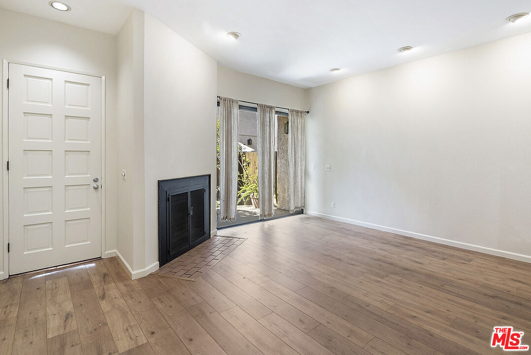2216 South Bentley Avenue, Unit 10 Los Angeles, CA 90064 - Photo 3 of 40 an empty room with wooden floor fireplace and staircase