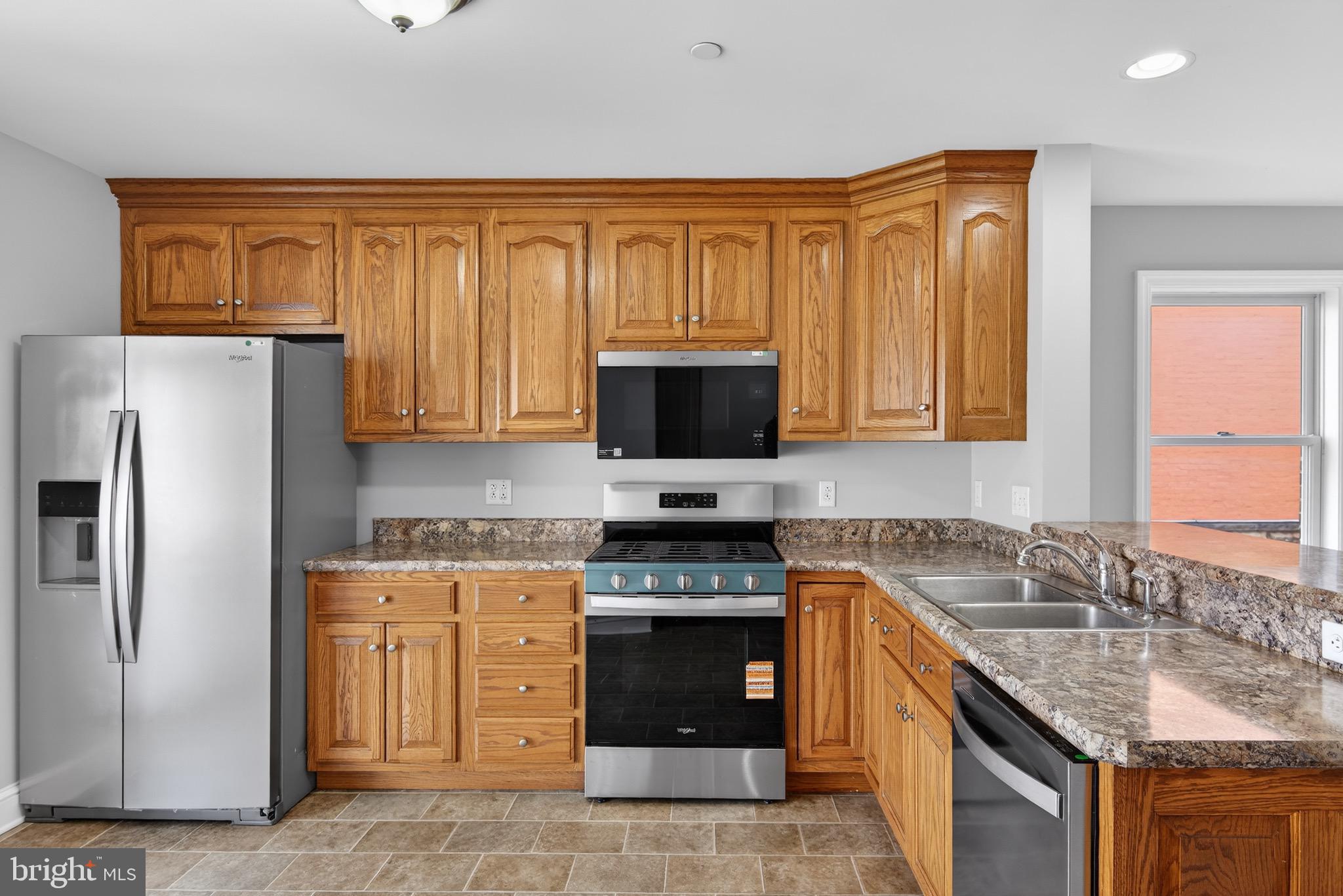 637 East Fulton Street Lancaster, PA 17602 - Photo 8 of 28 a kitchen with stainless steel appliances granite countertop a stove top oven a sink dishwasher and a refrigerator with wooden cabinets