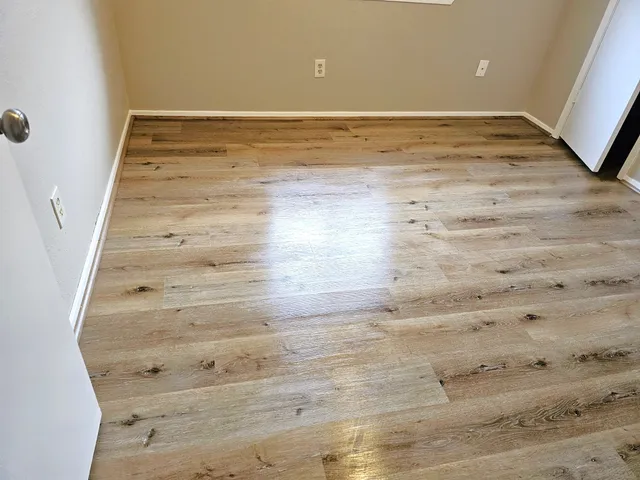an empty room with wooden floor and fan