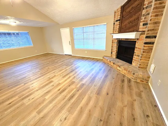 a view of empty room with wooden floor and fireplace