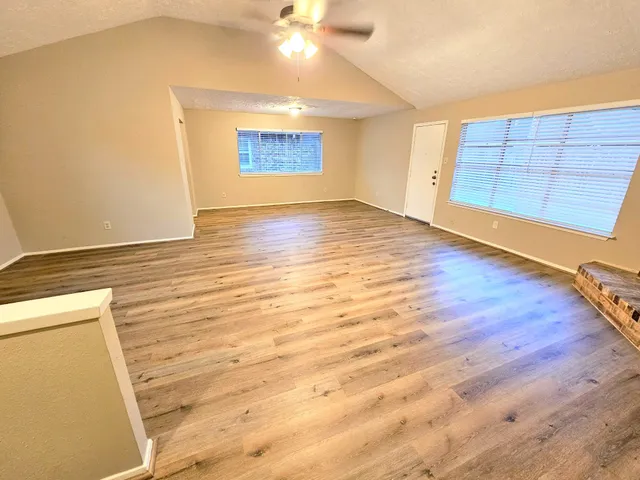 an empty room with wooden floor and windows