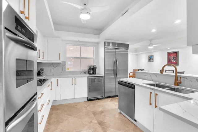 a kitchen with stainless steel appliances kitchen island granite countertop a dining table chairs and a refrigerator