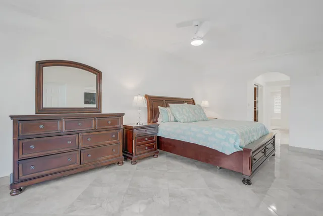 a bedroom with a bed mirror on dresser and a window