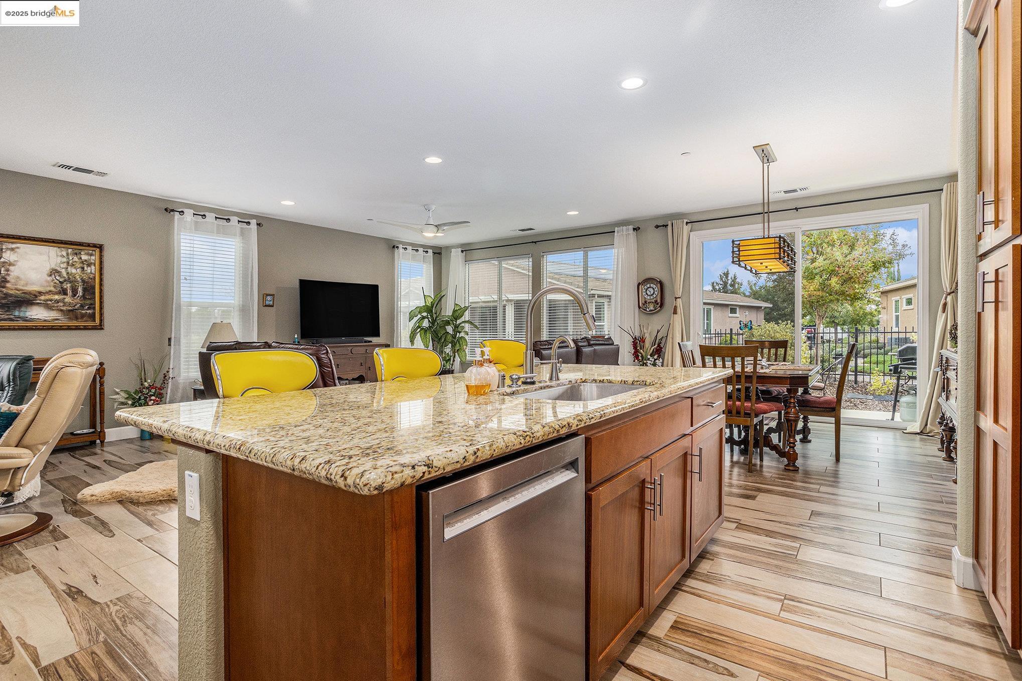 299 Marks Road Rio Vista, CA 94571 - Photo 38 of 39 Kitchen featuring brown cabinetry, light stone countertops, dishwasher, open floor plan, and a center island with sink