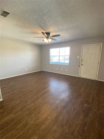 an empty room with wooden floor ceiling fan and windows