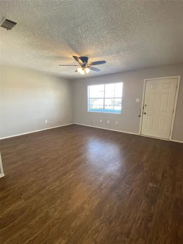 an empty room with wooden floor ceiling fan and windows