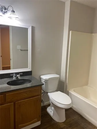 a bathroom with a granite countertop bathtub sink vanity mirror and toilet