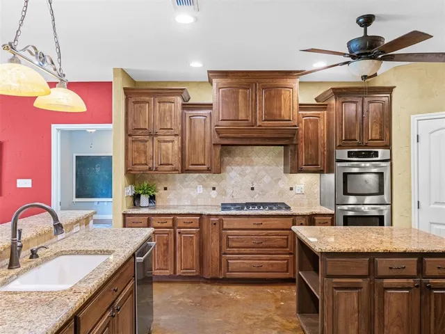 a kitchen with granite countertop kitchen island stainless steel appliances a sink stove top oven and microwave