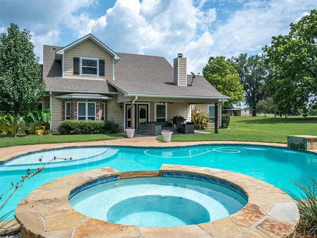 a view of swimming pool with lawn chairs and large trees