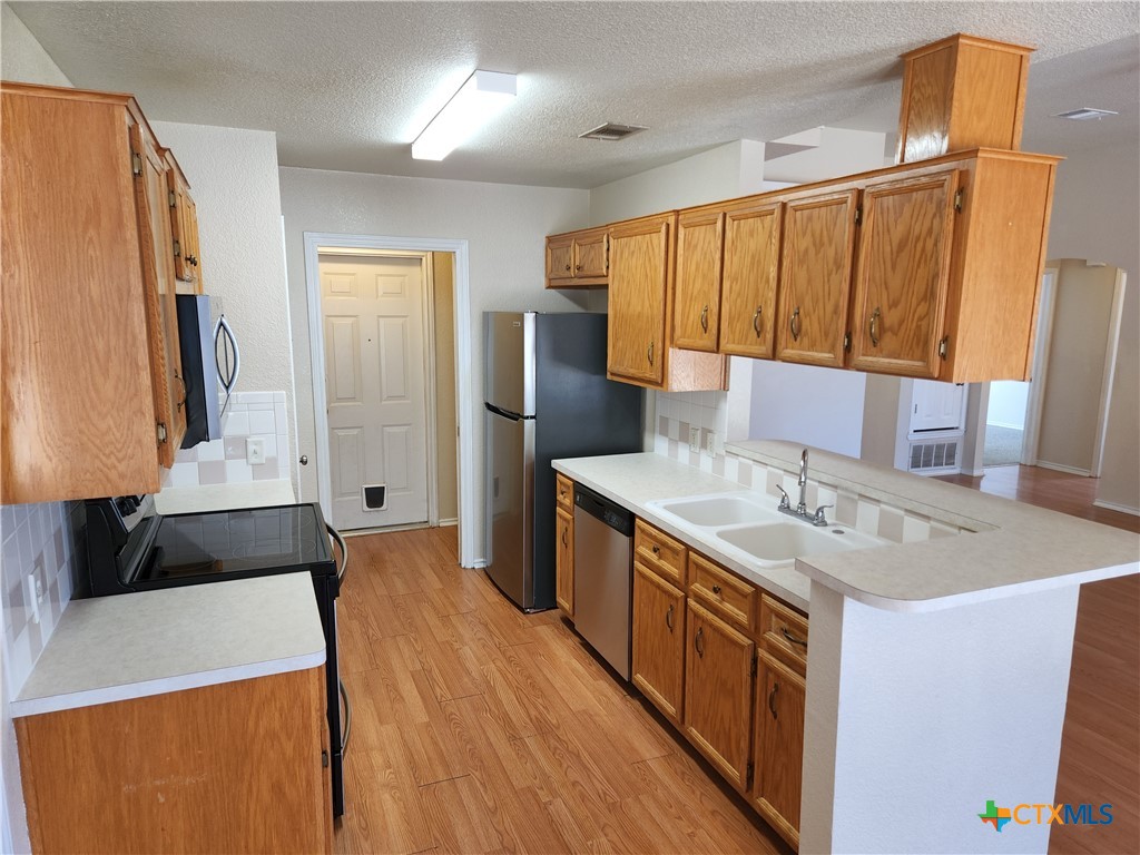 3407 Woodrow Drive Killeen, TX 76549 - Photo 3 of 10 a kitchen with stainless steel appliances a sink stove and a refrigerator