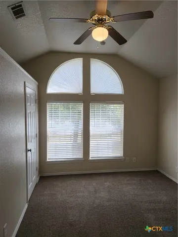 an empty room with windows and chandelier fan