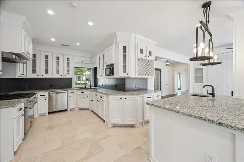 a large kitchen with stainless steel appliances kitchen island granite countertop a refrigerator and a wooden floors