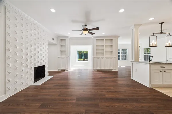 an empty room with wooden floor fireplace and windows