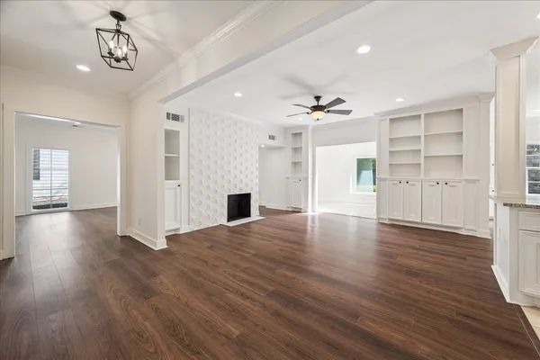 a view of an empty room with wooden floor and a ceiling fan