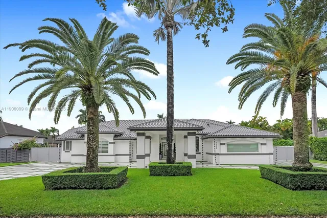 a view of a house with a yard and palm trees