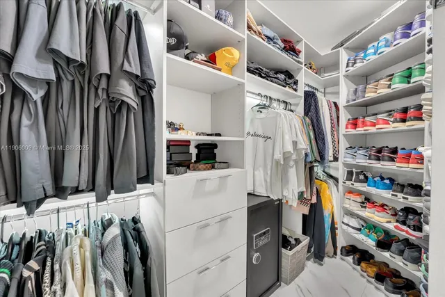 a view of walk in closet with clothes and shoes
