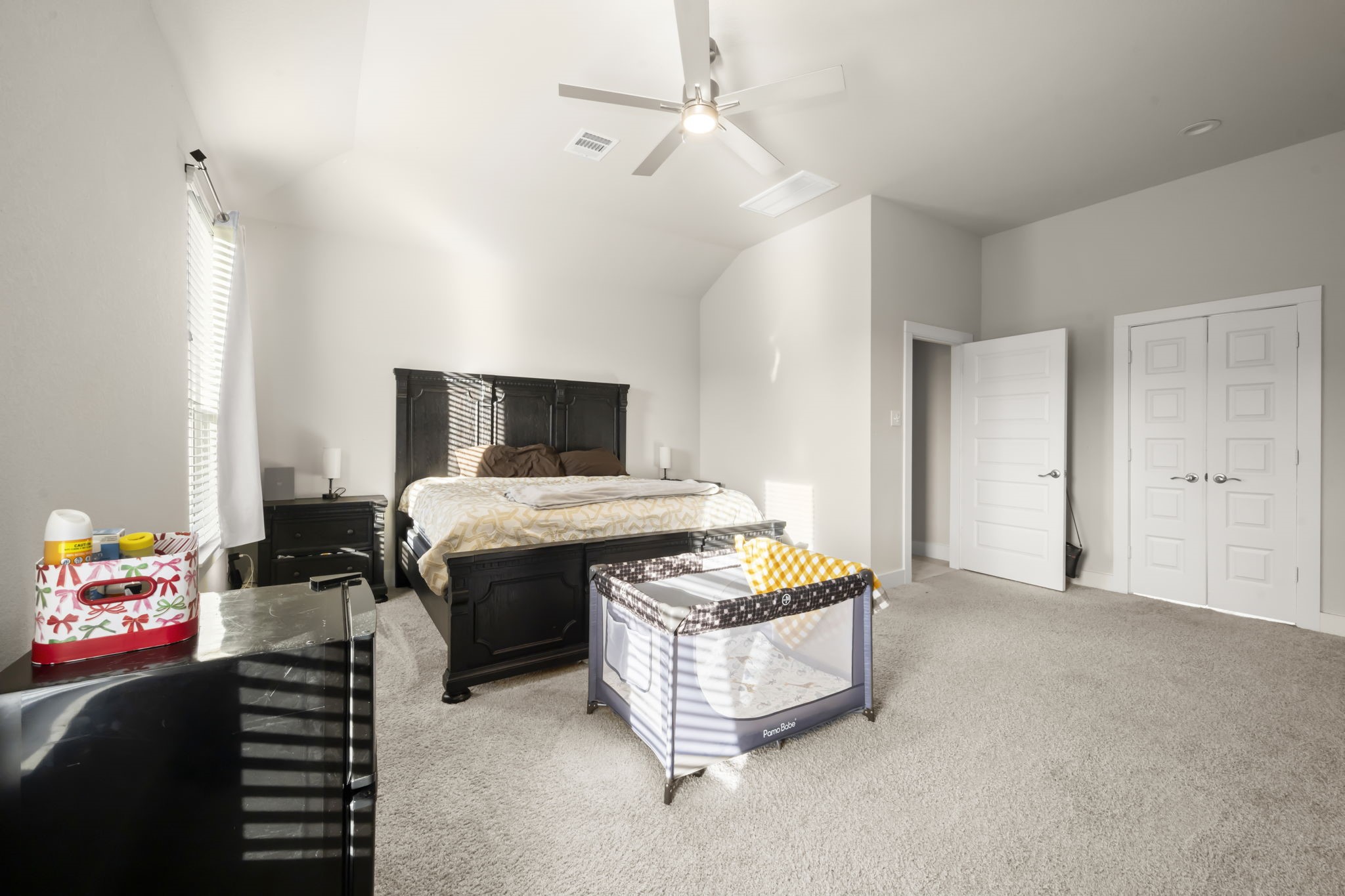 24715 Native Forest Spring, TX 77373 - Photo 20 of 37 Spacious bedroom with neutral colors, featuring a large bed, ceiling fan, and ample natural light. Carpeted floors and a double-door closet offer convenience and comfort. Perfect for a cozy, functional setup.