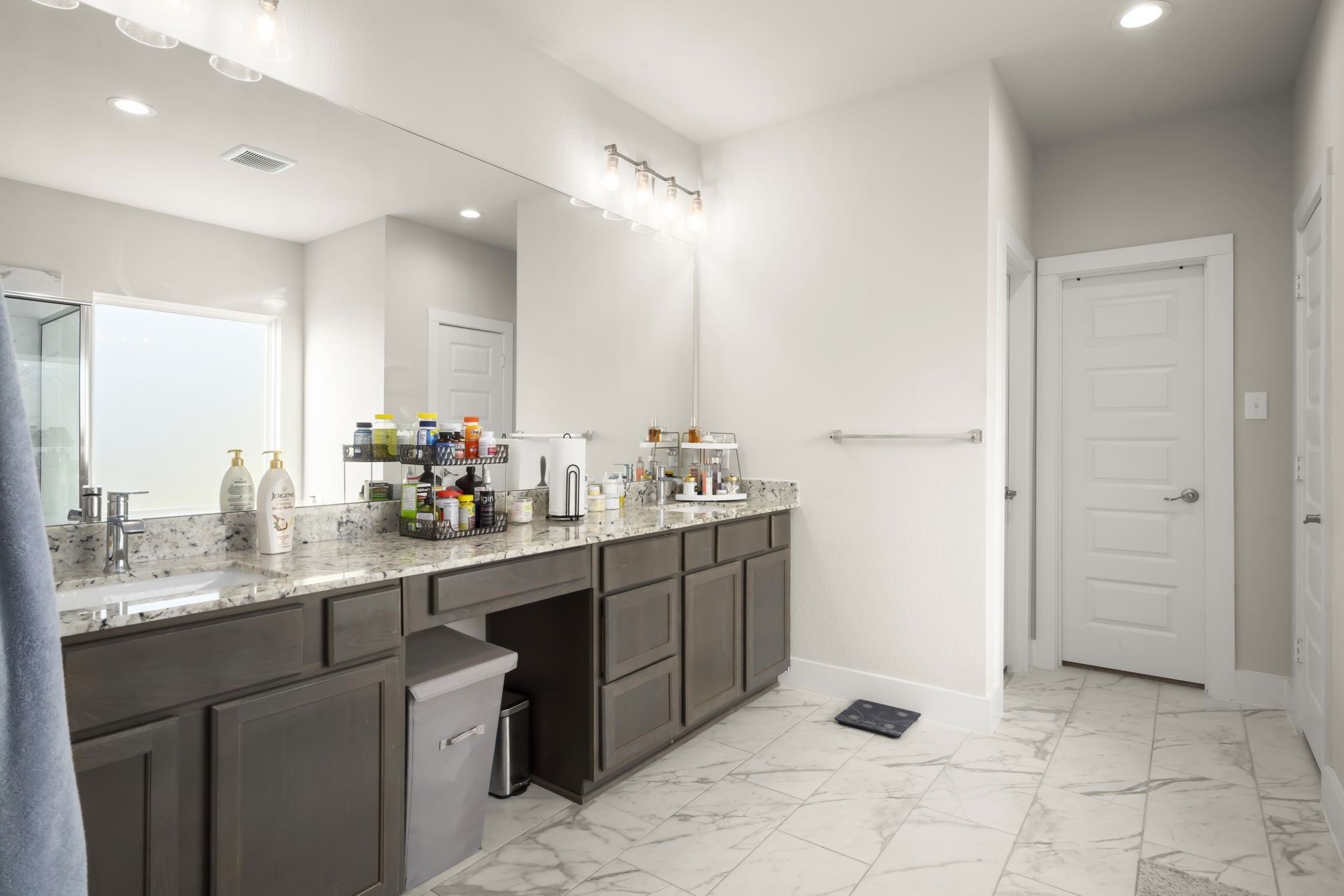 24715 Native Forest Spring, TX 77373 - Photo 21 of 37 This spacious bathroom features a large vanity with dual sinks, granite countertops, ample storage, and modern fixtures. The room is well-lit with recessed lighting and has a clean, contemporary design with marble-style tile flooring.