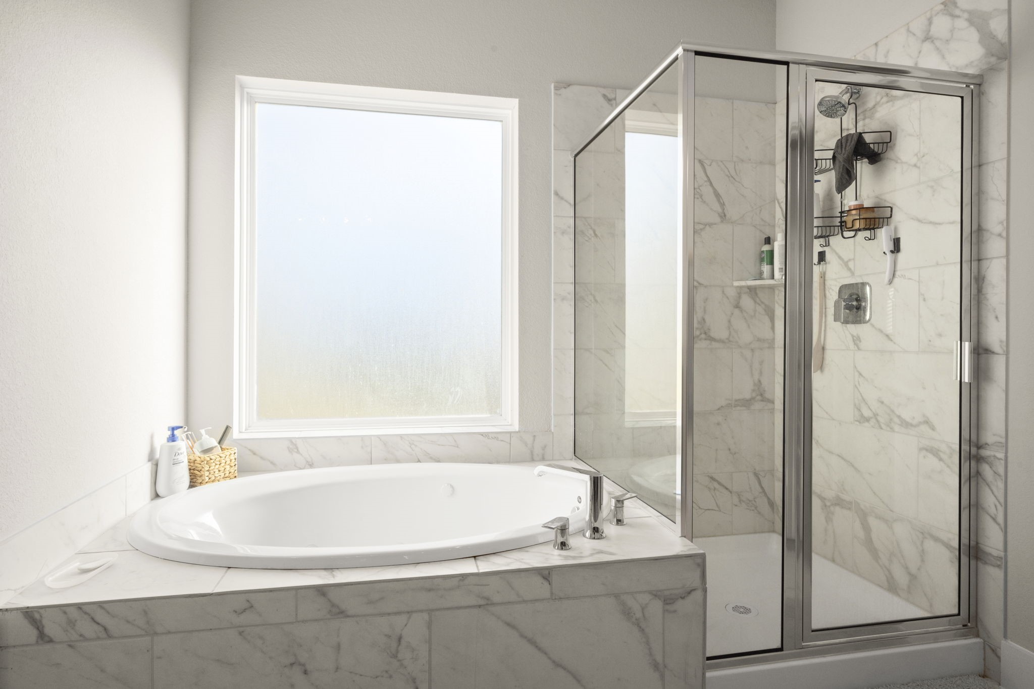 24715 Native Forest Spring, TX 77373 - Photo 22 of 37 This bathroom features a luxurious marble design with a large soaking tub and a separate glass-enclosed shower, offering a bright and modern space.
