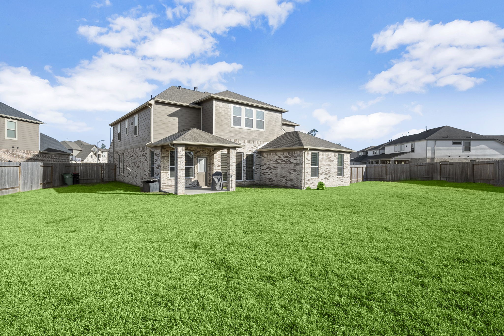 24715 Native Forest Spring, TX 77373 - Photo 34 of 37 Spacious two-story brick home with a large, well-maintained backyard. Features a covered patio, perfect for outdoor entertaining. Located in a suburban neighborhood with a fenced yard for privacy.