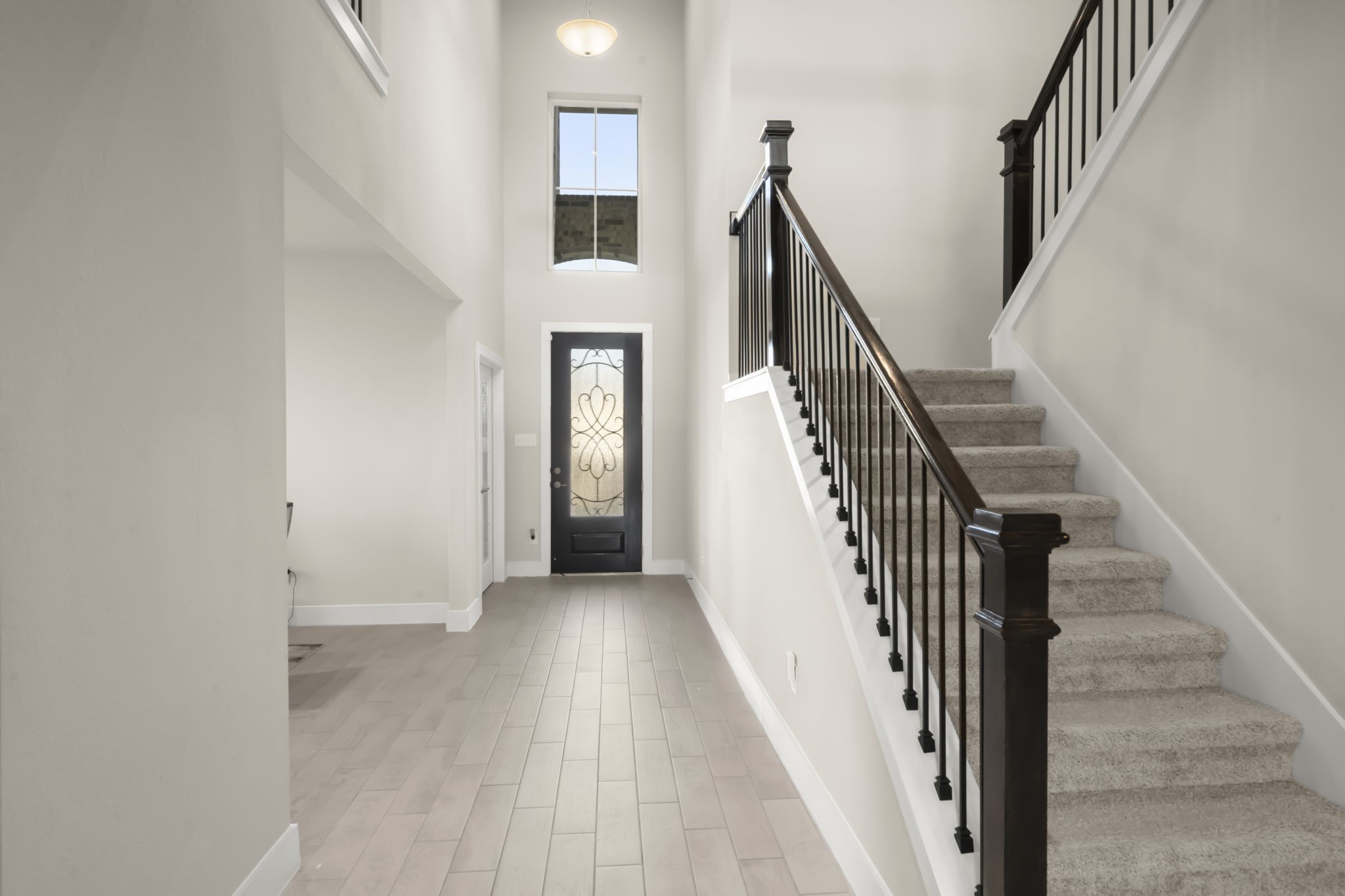 24715 Native Forest Spring, TX 77373 - Photo 6 of 37 Bright entryway with high ceilings, elegant staircase, and a stylish front door. The space has a modern, open feel with light wood flooring and neutral walls.