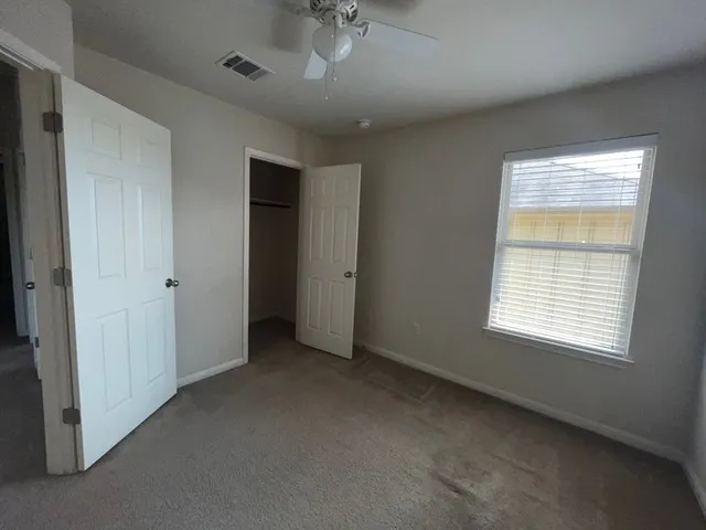 an empty room with a window and a ceiling fan
