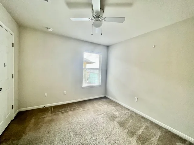 an empty room with closet and a ceiling fan