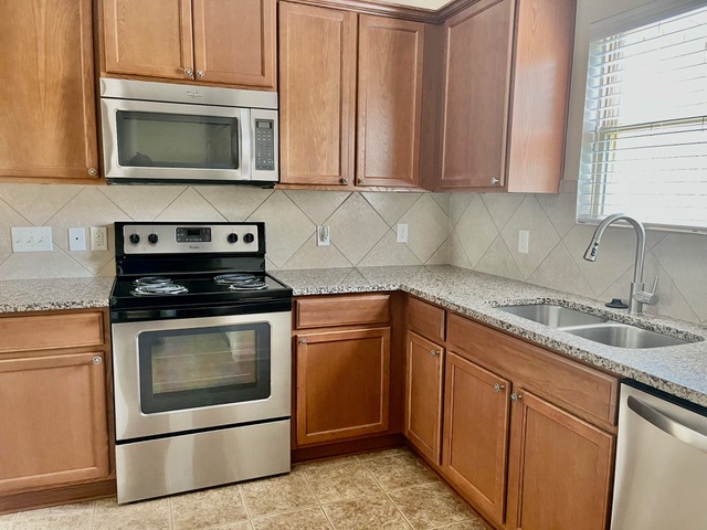 5425 Falling Leaf Lane Austin, TX 78744 - Photo 23 of 28 a kitchen with stainless steel appliances granite countertop a sink stove and microwave