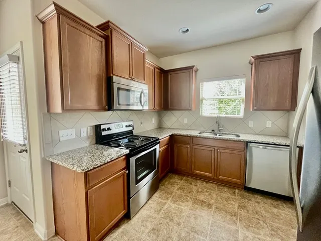 a kitchen with stainless steel appliances granite countertop a refrigerator and a sink