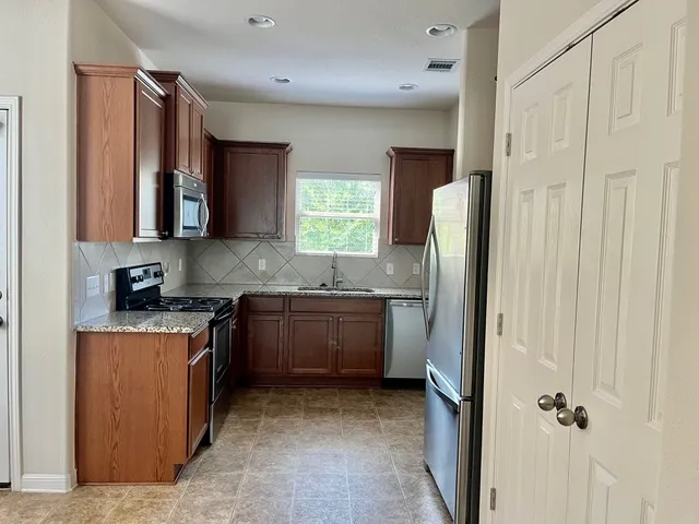 a kitchen with stainless steel appliances granite countertop a refrigerator and a sink