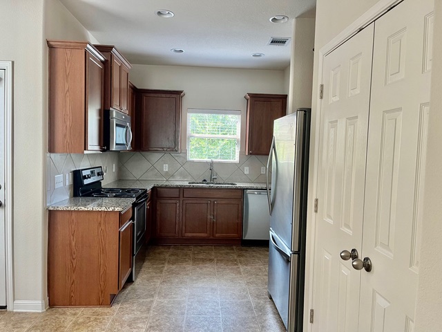 5425 Falling Leaf Lane Austin, TX 78744 - Photo 8 of 28 a kitchen with stainless steel appliances granite countertop a refrigerator and a sink